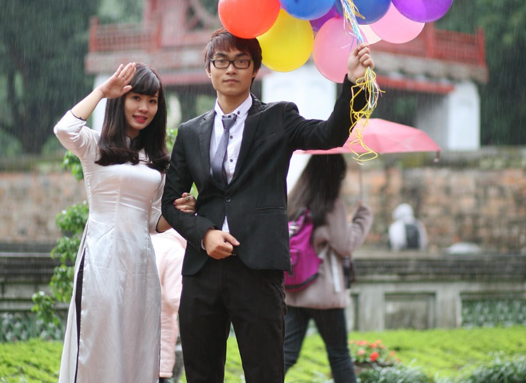 rained on summer event. Bride and groom in rain with balloons